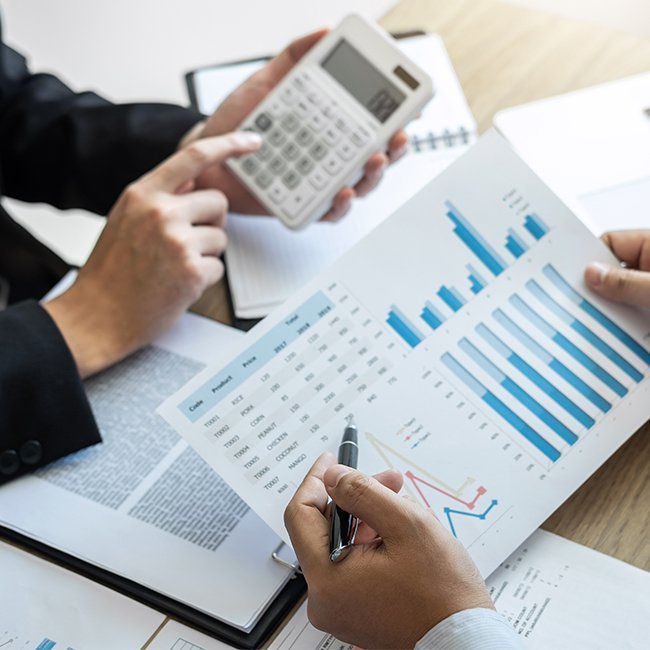 Small business bookkeeper organizing financial documents on desk with calculator and laptop